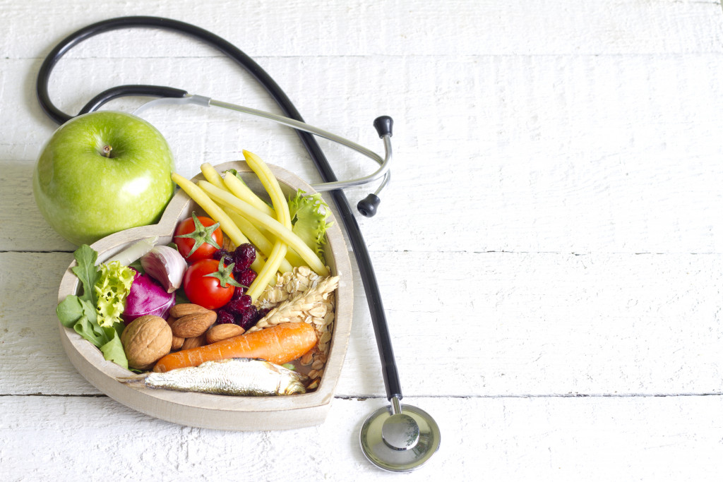 fruits and vegetables in a heart-shaped container with a stethoscope alongside it