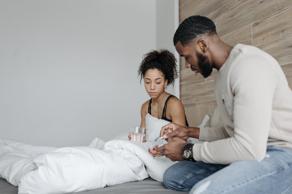 woman-sick-in-bed-man-gives-medicine