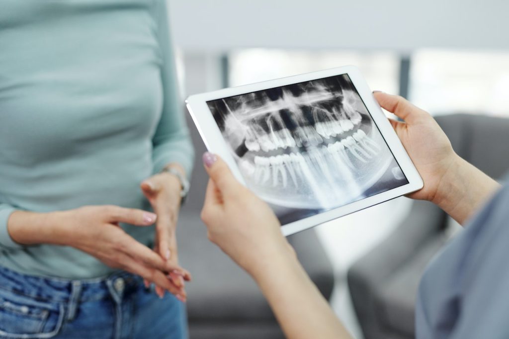 dentist looking at dental imaging with female patient