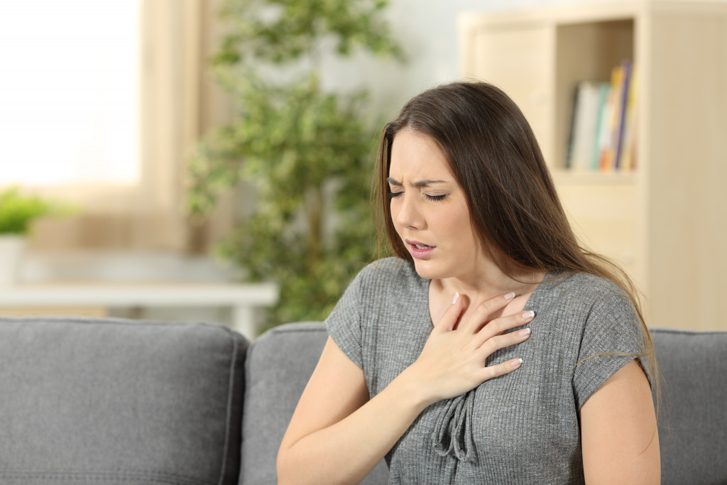A woman holding her aching chest at home