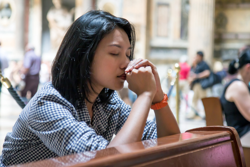 A woman kneeling on a pew while praying